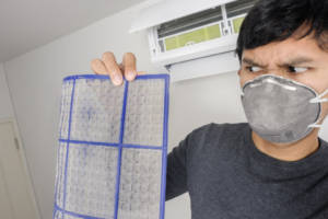 Man cleaning dirty air conditioner filter